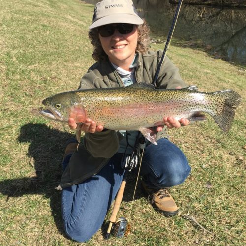 My wife, Melanie, kneeled down holding her monster rainbow trout caught at the spring creek in Ohio