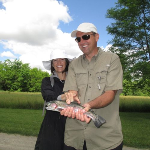 A middle-aged couple enjoying their time at the spring creek while holding a trout
