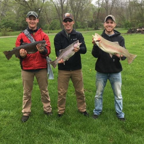Three young men standing holding their big catch up of the day