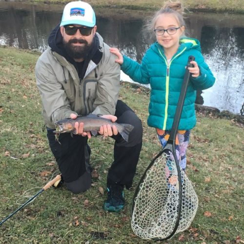 My son kneeled down holding a trout next to his niece, Eva, who helped him net it