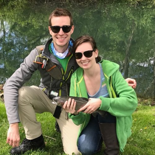 A young couple kneeled down holding their trout