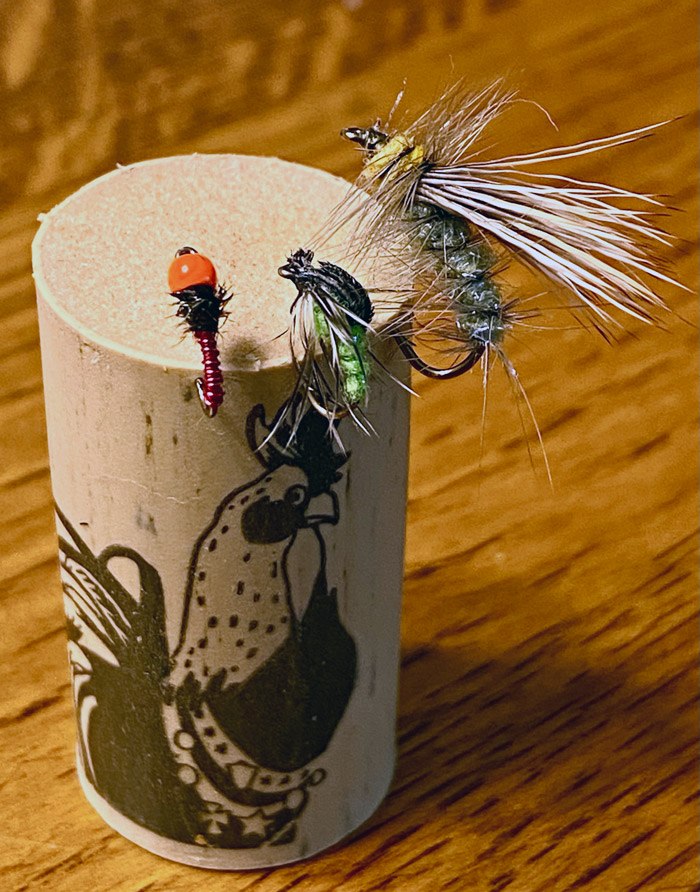 A cork on a table with three fly patterns hooked into the cork