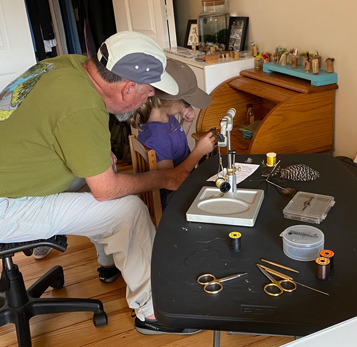 Eva and Greg sitting down working on a fly at Eva's fly tying roll desk.