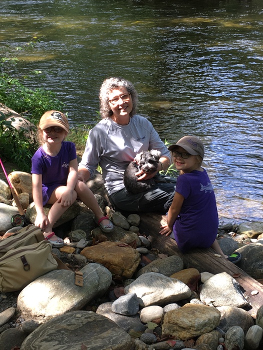 Melanie, Lila, Eva and Willow all sitting on the rock bank next to the stream facing the camera.