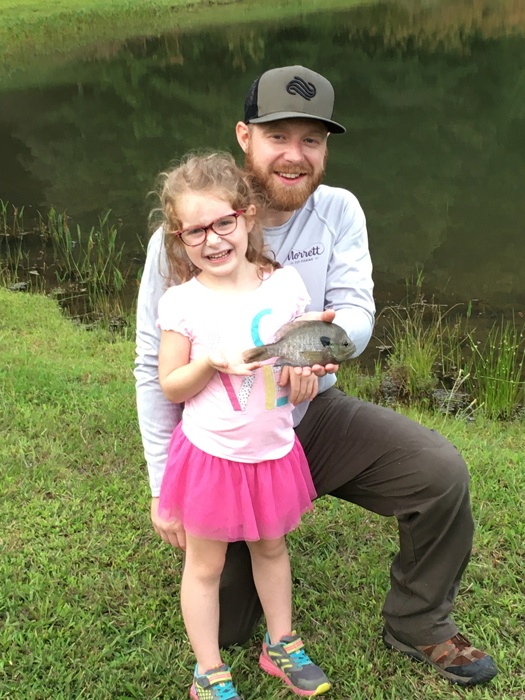 Andy crouched behind Lila standing while holding her blue gill.