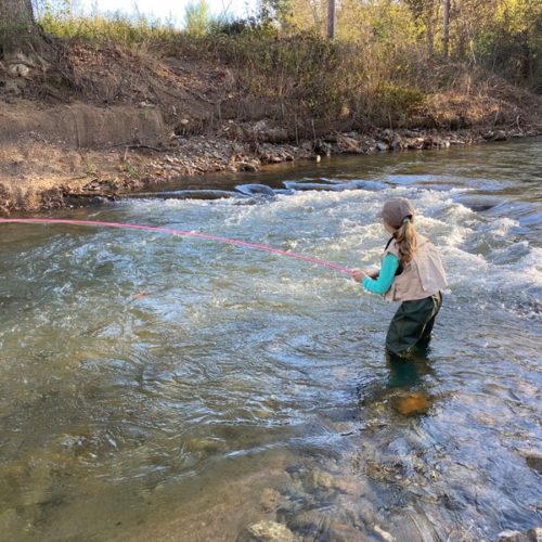 A girl wading in the river casting upstream